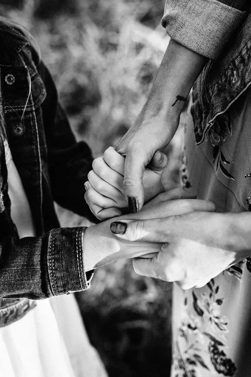 Black and white close-up of two adults and a child holding hands together