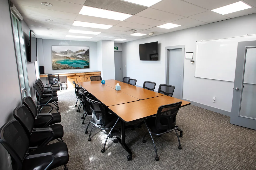 Conference room with a long table seating ten, wall-mounted TV, and whiteboard